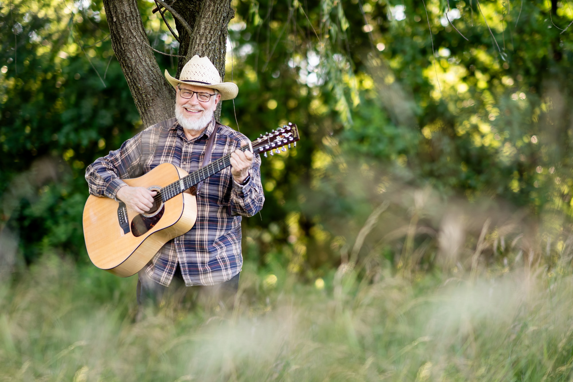 A guitarist standing in the woods playing music