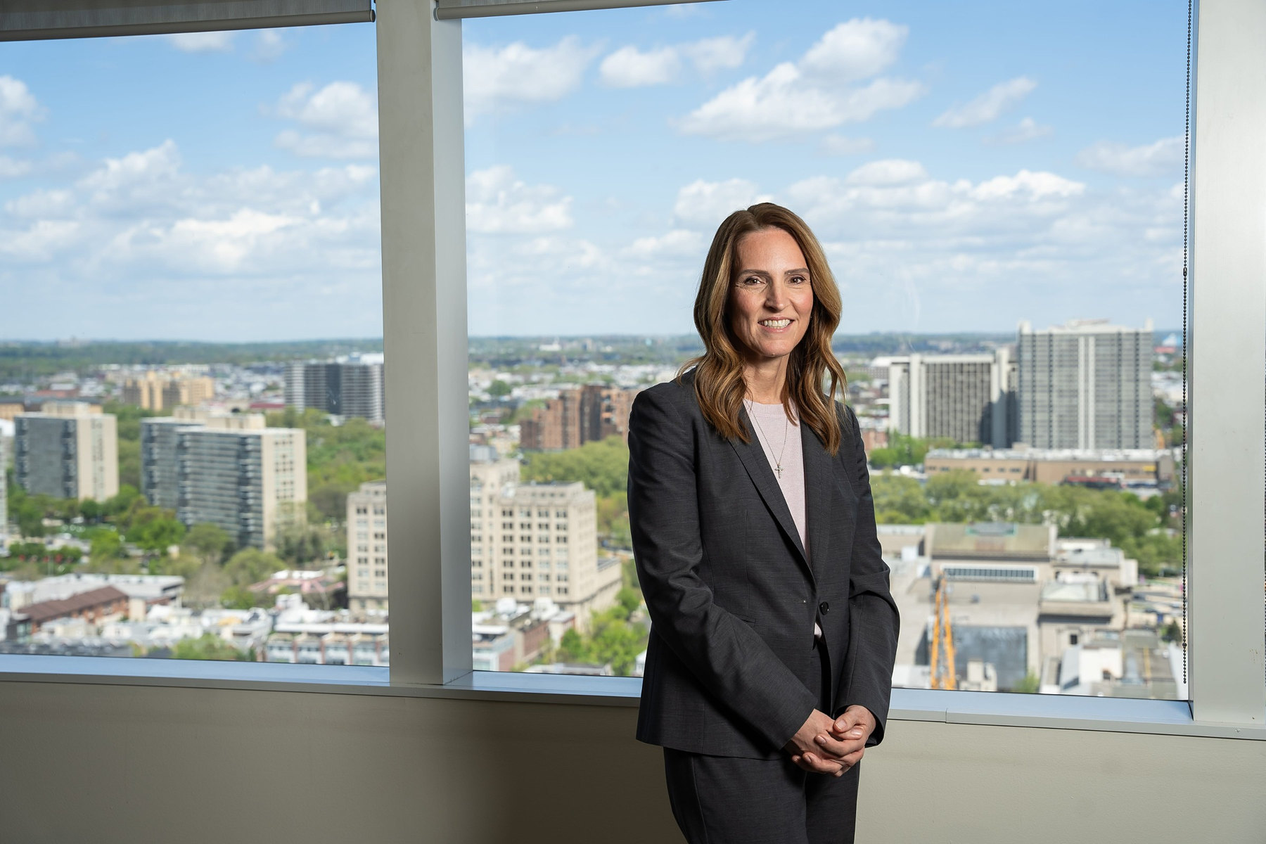 Executive standing beside a window with a city skyline view