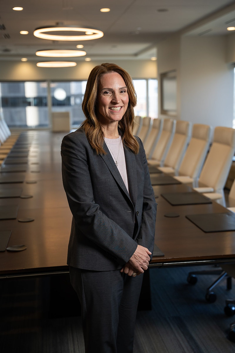 Executive standing at a long boardroom table in a vertical portrait