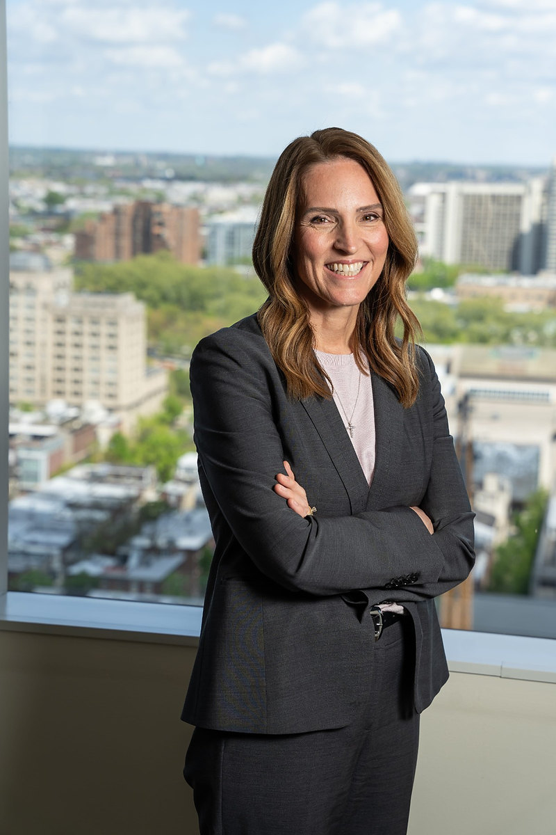 Executive with arms crossed in front of a city skyline window