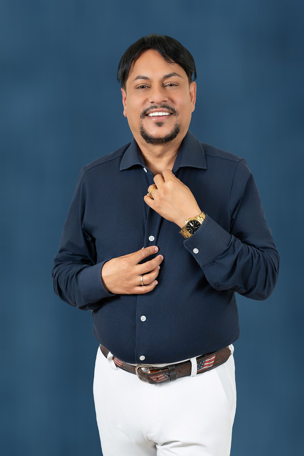 Studio headshot of a business owner in a navy shirt against a blue backdrop