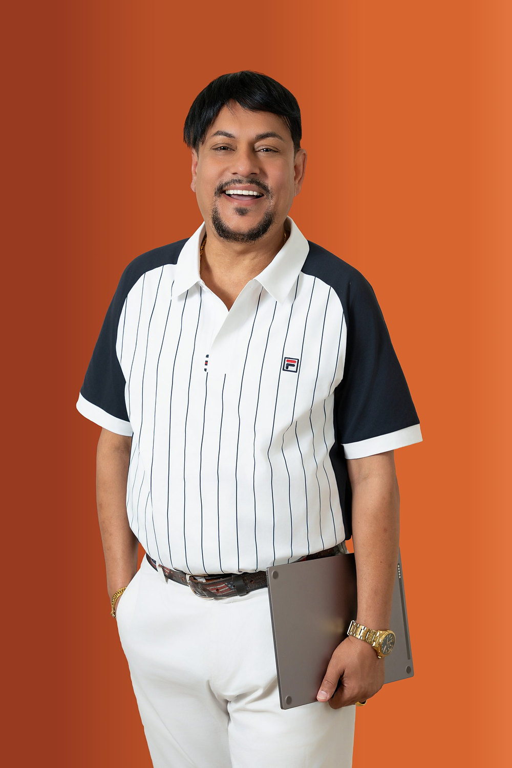 Studio headshot of a smiling professional holding a tablet against an orange backdrop